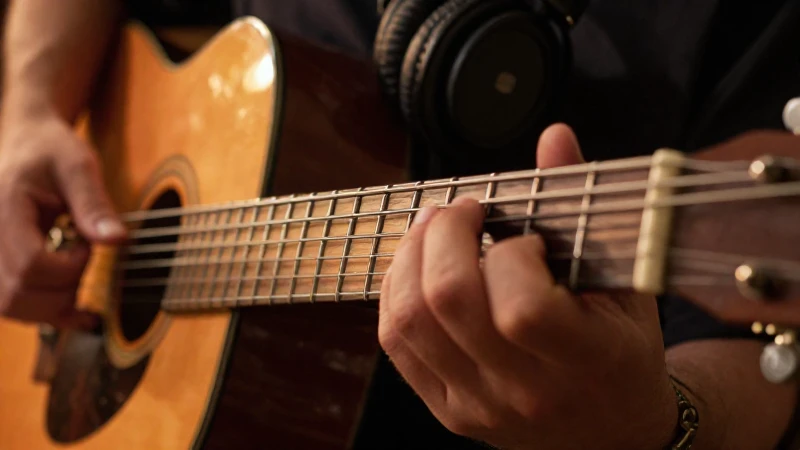 Manos de un guitarrista tocando las cuerdas sobre un mástil de madera en un estudio.