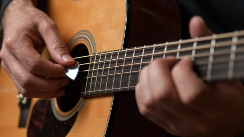 Primer plano comparativo de manos tocando un guitarrista con púa y con los dedos.