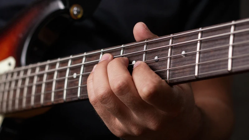 Primer plano de la mano izquierda de un guitarrista ejecutando una técnica precisa sobre las cuerdas.