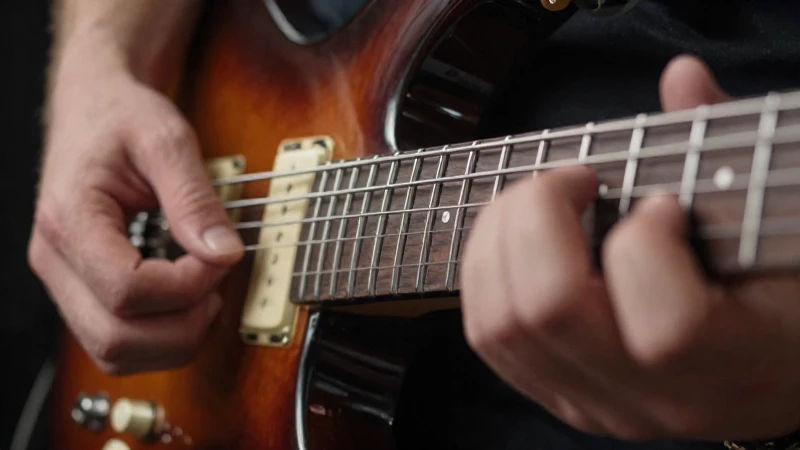 Primer plano de las manos de un guitarrista realizando técnica de sweep picking en una guitarra eléctrica.