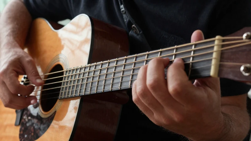 Manos de un guitarrista realizando ejercicios técnicos sobre el diapasón de una guitarra acústica.