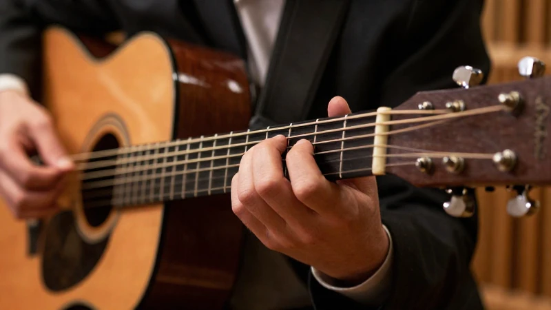Manos de un guitarrista ejecutando acordos complejos sobre el mástil de una guitarra acústica.